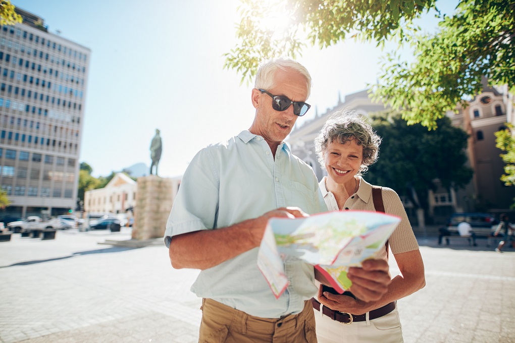 Portrait of happy senior couple using city map for finding their location. Mature couple travelling in a city with a road map.