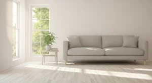 A clean and modern apartment living room with simple furniture, a plant, and a large window with a view of trees.